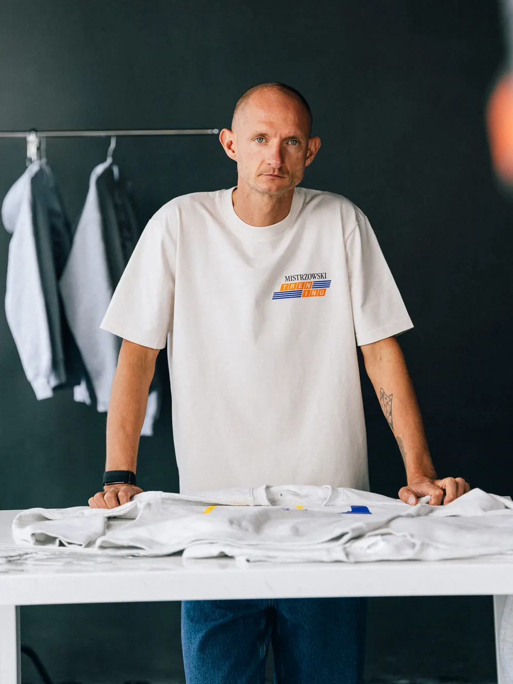 Marcin w koszulce Sober Lab przy stole z ubraniami